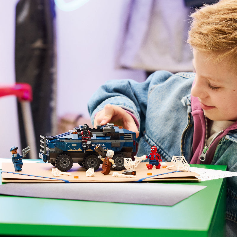 Child playing with a toy vehicle and figures on a table