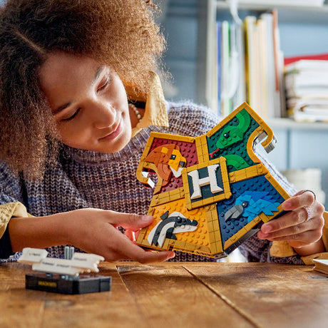 Person holding a colorful Harry Potter-themed puzzle piece on a wooden table.