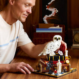 Man holding a LEGO owl on a table with a detailed LEGO set in the background