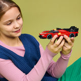 Young girl holding a red toy car against a green background