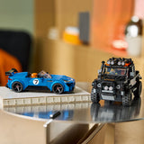 Two LEGO toy cars displayed on a glass tabletop in a real indoor setting with a blurred background: a blue sports car with the number 7 on the left and a black off-road vehicle on the right.