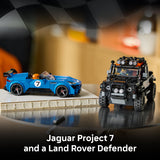 Two toy cars, a blue Jaguar Project 7 and a black Land Rover Defender, on a reflective surface with a blurred background.