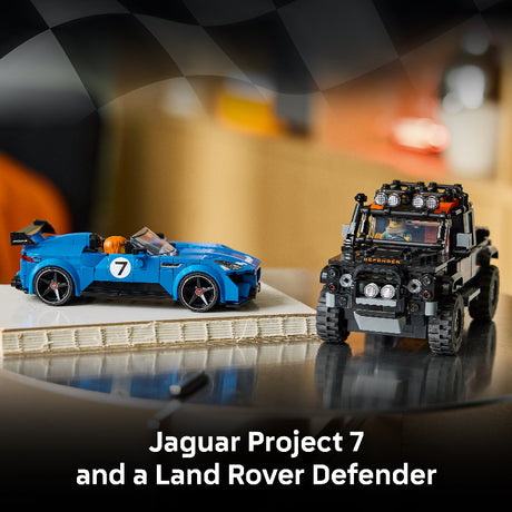 Two toy cars, a blue Jaguar Project 7 and a black Land Rover Defender, on a reflective surface with a blurred background.