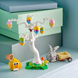 LEGO set with a tree, birds, and animals on a light blue surface.