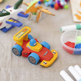 Colorful toy race car on a textured surface with toys and markers in the background