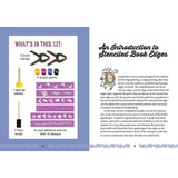 A printed booklet or instruction sheet showing a kit contents panel on the left with illustrations of tools and paint brushes, and a right-hand page with text titled 'An Introduction to Stenciled Book Edges' and decorative lettering.