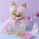 Pink fluffy cat with green accents and a 'Muffin' heart tag on a light purple background.