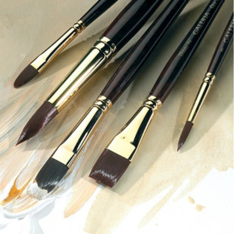 Set of acrylic paintbrushes with gold accents on a textured beige background