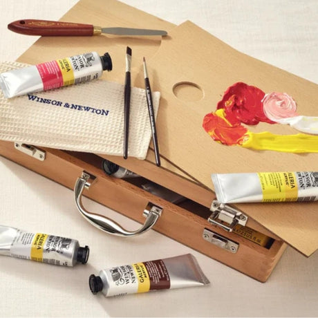 Art supplies including paint tubes, brushes, and a palette with floral painting on a beige background.