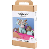 Amigurumi cow kit packaging with a crochet toy and tools on a white background