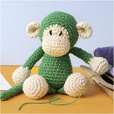 Crocheted monkey toy on a yellow surface with a light blue background