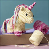 Crocheted unicorn toy with yarn on a purple surface