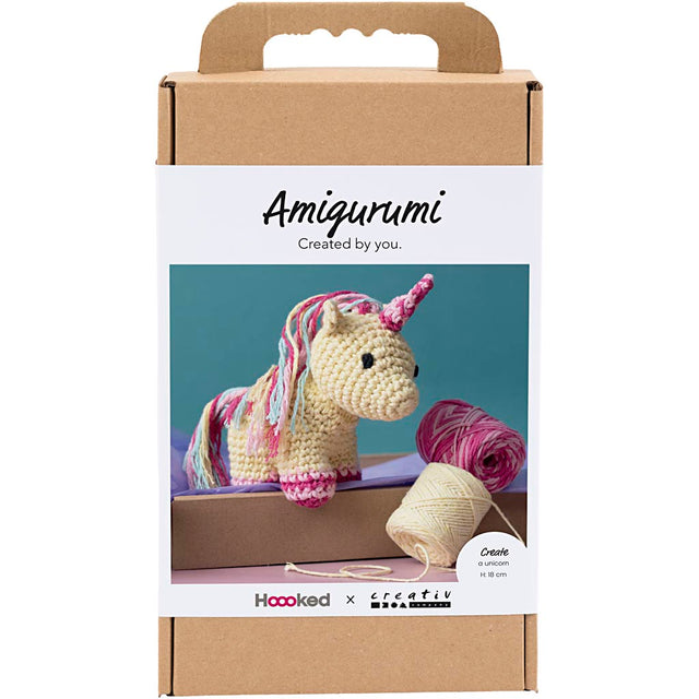 Amigurumi unicorn kit packaging with yarn and crochet hook on a white background