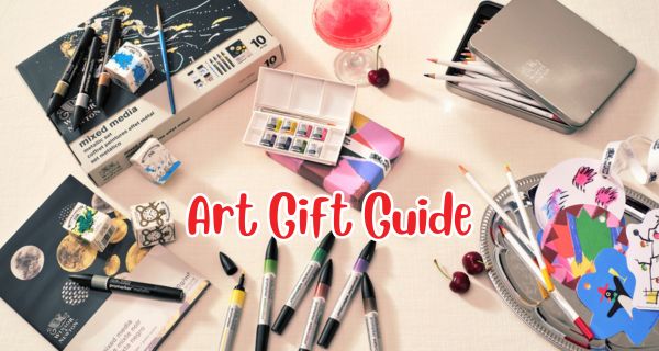 Art supplies and stationery items on a table with 'Art Gift Guide' text overlay.