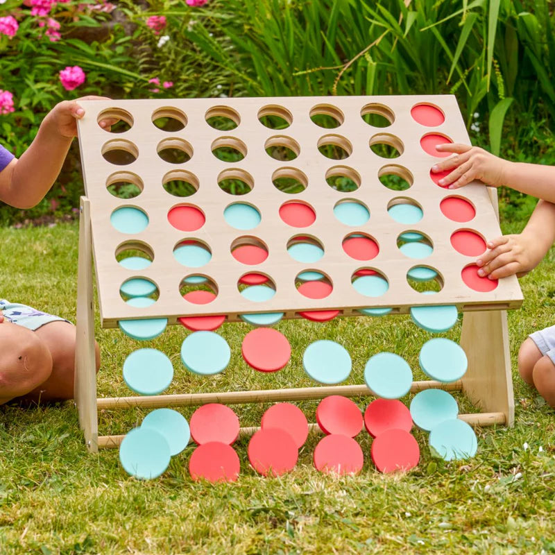 Children playing with a large outdoor version of Connect Four on a grassy area.