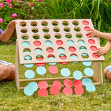 Children playing with a large outdoor version of Connect Four on a grassy area.