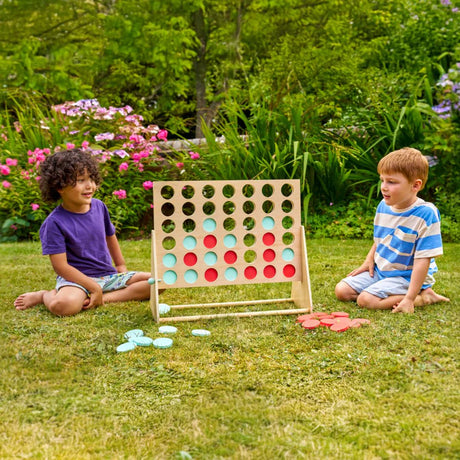 Two children playing with a large outdoor connect-four game in a garden.
