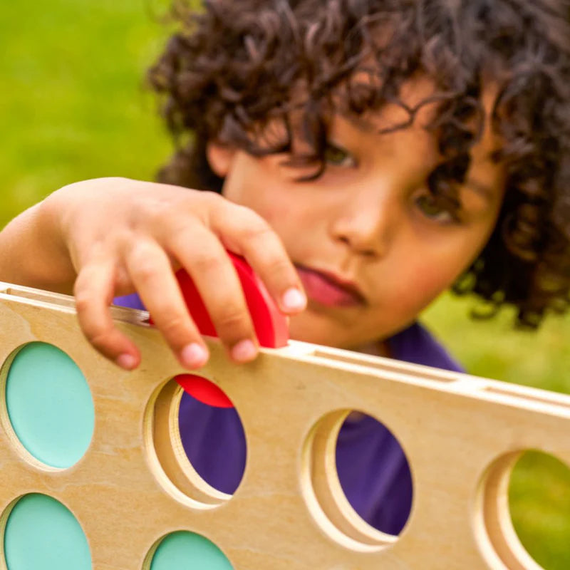Child playing with a colorful wooden game board outdoors