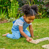 Young girl playing with wooden blocks on grass