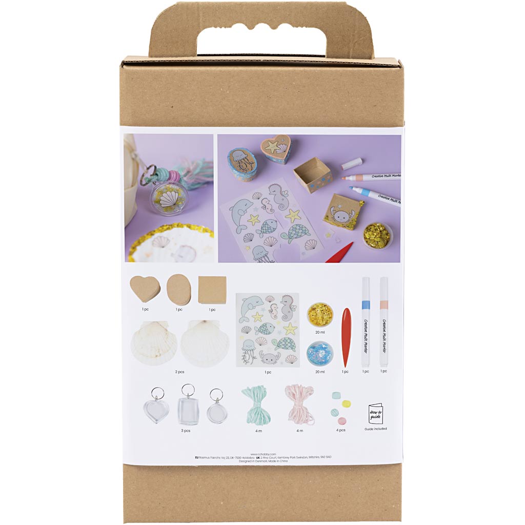 Cardboard box with craft materials and tools on a white background