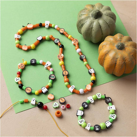 Halloween-themed beaded necklaces on a green surface with pumpkins.