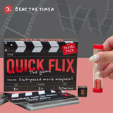 Quick Flix travel pack game set featuring a black clapperboard-style box, playing cards, a small sand timer with a hand holding it, and a dice cube on a pink and gray background.