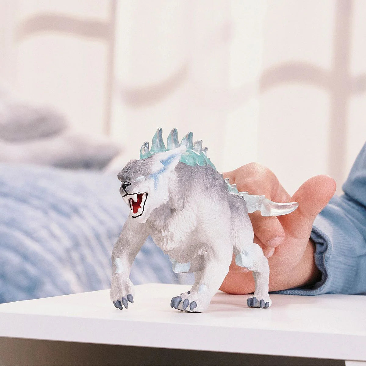 Toy dinosaur figure with blue energy effect held by a person on a white surface.