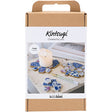 Kintsugi kit packaging with decorative items and a candle on a white background