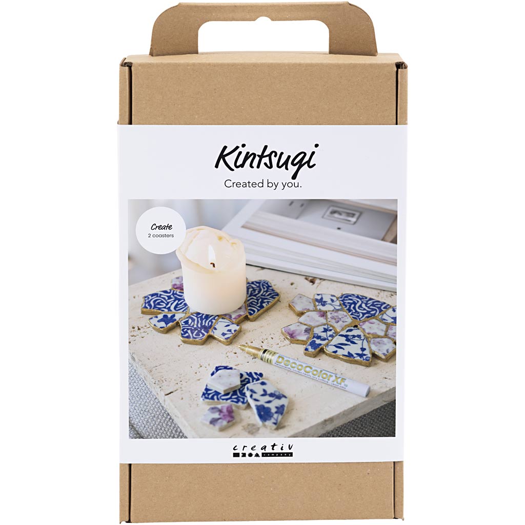 Kintsugi kit packaging with decorative items and a candle on a white background