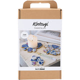 Kintsugi kit packaging with decorative items and a candle on a white background