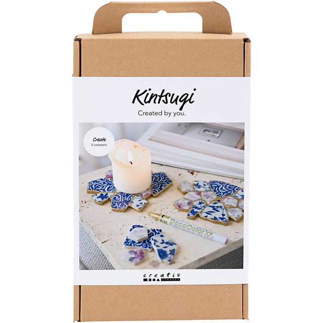 Kintsugi kit packaging with decorative items and a candle on a white background