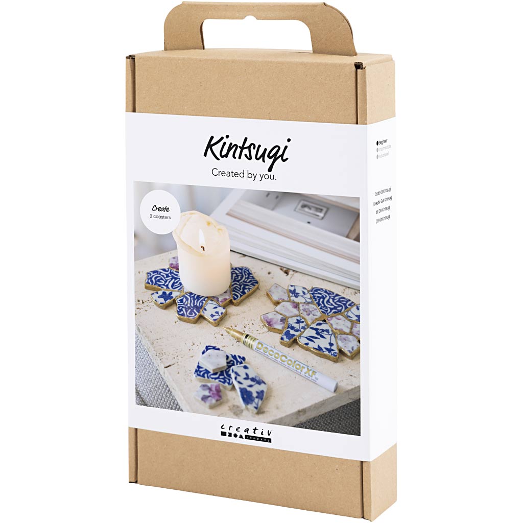 Kintsugi kit packaging with decorative items and a candle on a white background