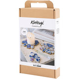 Kintsugi kit packaging with decorative items and a candle on a white background
