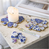 Decorative coasters with blue and white patterns on a surface with a candle and DecoColor XT tube.