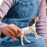 Child holding a toy horse with a spotted pattern on a blue surface