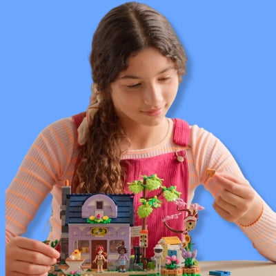 Girl playing with a LEGO set against a blue background