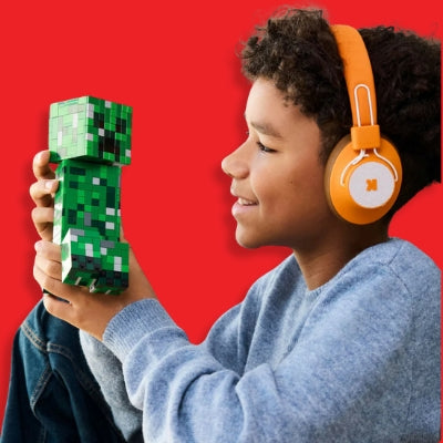 Child wearing orange headphones holding a Minecraft LEGO toy figure against a red background