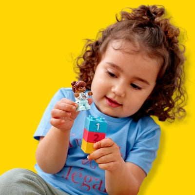 Child playing with colorful building blocks against a yellow background