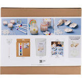 Product packaging with images of candles, clay, and tools on a blue background