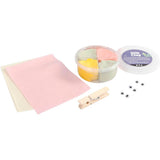 Silk Clay kit with pink paper, containers of clay, a clothespin, and small beads on a white background.