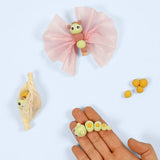 Butterflies sculpted from silk clay and coloured tissue paper next to a hand holding a clay caterpillar on a white background.
