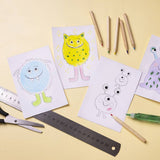 Children's drawings of colorful monsters on paper with art supplies on a yellow background