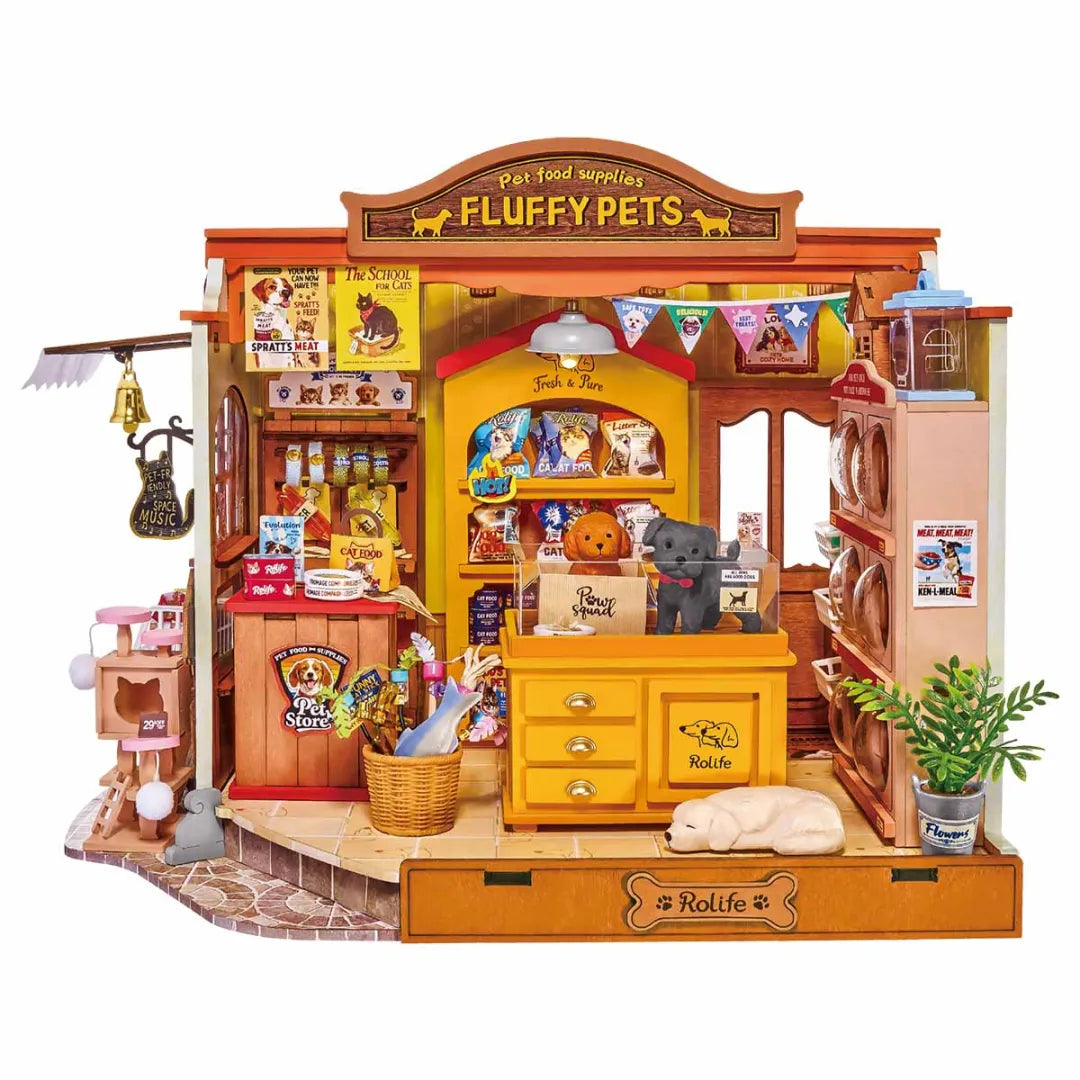 A wooden pet store playset with a detailed miniature shop facade, counter, shelves, hanging accessories, and a small plant, shown on a plain white background.