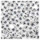 White letter beads with black letters scattered on a white background