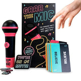 Grab the Mic karaoke party game set with a black and pink foam microphone, colorful cards, and a black instruction box, shown with a person's hand reaching toward it on a white background.