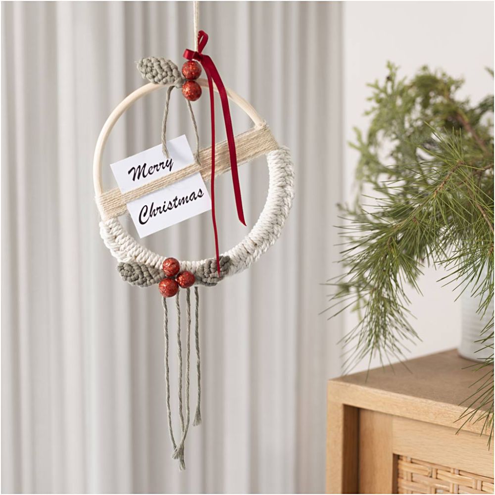 Decorative macrame wreath with 'Merry Christmas' card on a neutral background