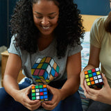 Two people holding Rubik's Cube puzzles in a casual setting.