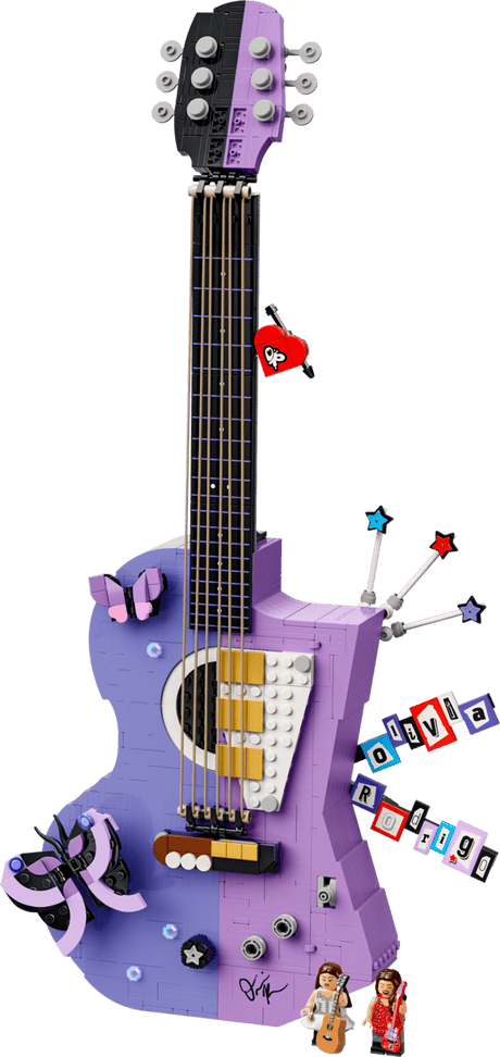 A purple and lavender toy guitar with various colorful accessories and small character figures, shown against a solid green background.