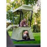 Children playing in a green playpen with slide and canopy in a park.