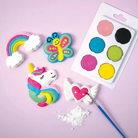 Colorful candy decorations including a rainbow, butterfly, unicorn, and heart with wings on a pink background.